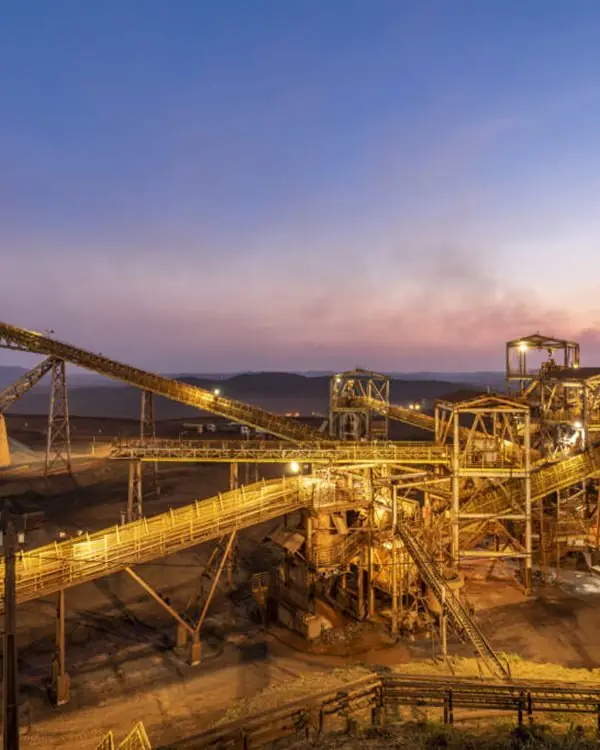 Planta de beneficiamento mineral com correias transportadoras ao entardecer