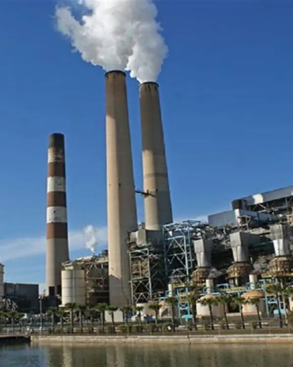 Usina termoelétrica à beira d'água, com as chaminés em operação